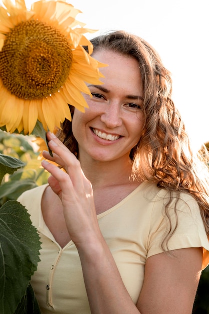 Kostenloses Foto smiley-frau, die mit sonnenblume aufwirft