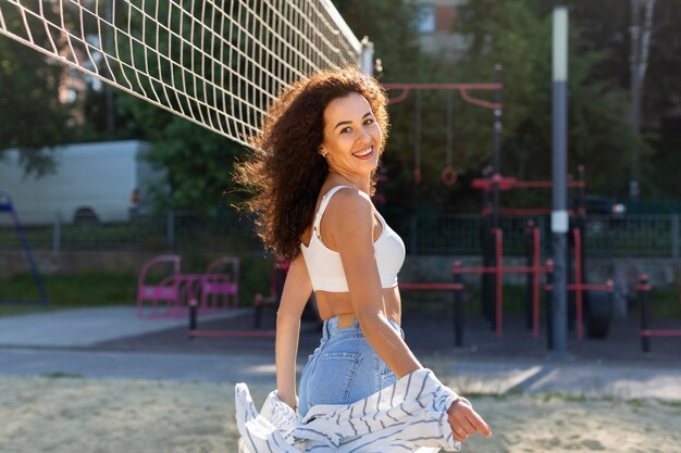 Smiley-Frau, die neben einem Volleyballfeld draußen aufwirft