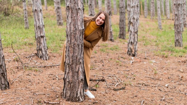 Smiley-Frau, die sich hinter einem Baum versteckt