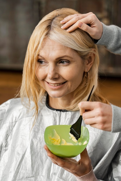 Smiley-Frau, die sich zu Hause vom Friseur die Haare färben lässt