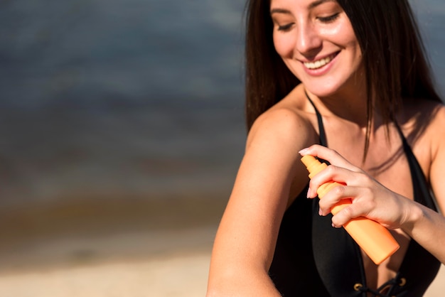 Smiley-Frau, die Sonnenschutz am Strand anwendet