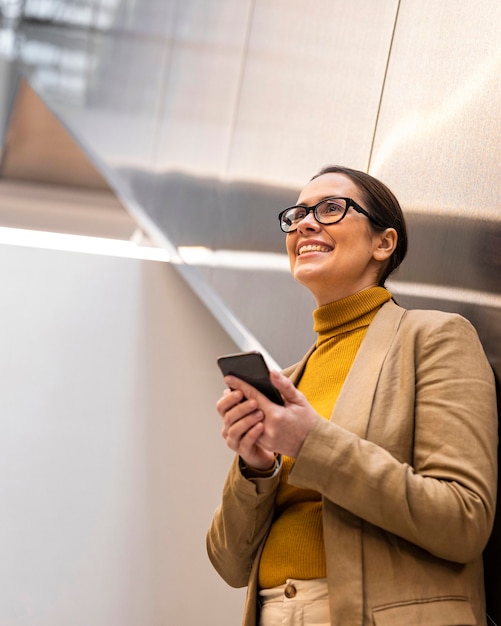 Smiley-Frau, die Telefon mittlerer Schuss hält