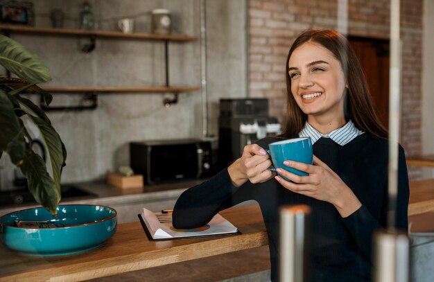 Smiley-Frau, die während eines Treffens Kaffee trinkt
