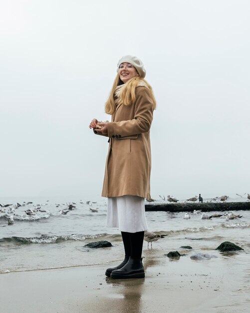 Smiley-Frau draußen am Strand im Winter