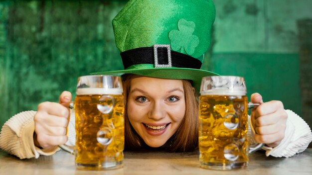 Smiley Frau feiert st. Patrick's Day mit Getränken an der Bar