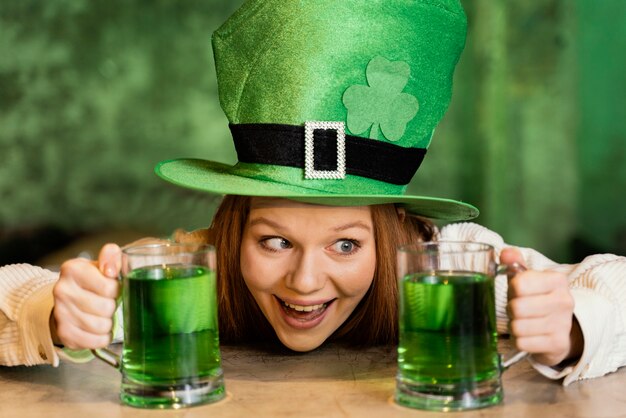 Smiley Frau feiert st. Patrick's Day mit Getränken