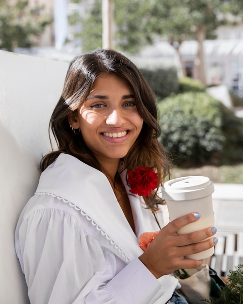 Smiley Frau im Freien mit Kaffeetasse und Blumen