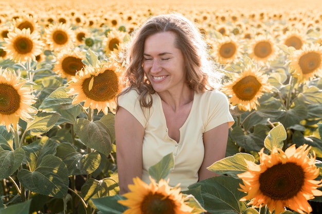 Smiley-Frau im Sonnenblumenfeld, das aufwirft