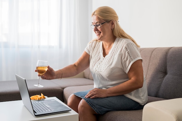 Smiley-Frau in Quarantäne, die ein Getränk mit Laptop trinkt