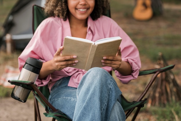 Smiley Frau liest Buch beim Camping im Freien
