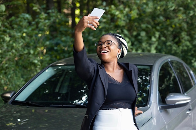 Smiley-Frau macht ein Selfie mit ihrem brandneuen Auto