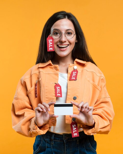 Smiley-Frau mit Brille, die Kreditkarte hält, während in Verkaufsanhänger bedeckt wird