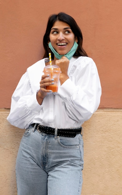 Kostenloses Foto smiley-frau mit gesichtsmaske und saftschale