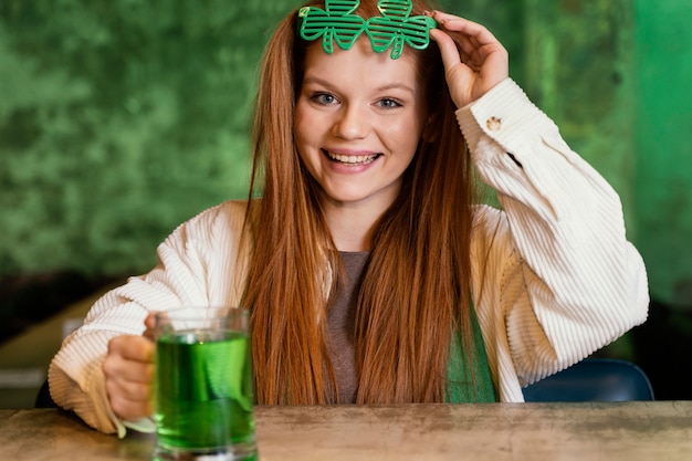 Smiley-Frau mit Kleeblattgläsern, die st feiern. Patricks Tag an der Bar