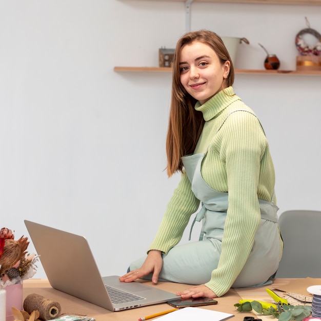 Smiley-Frau mit Laptop, der an einem Blumenladen arbeitet