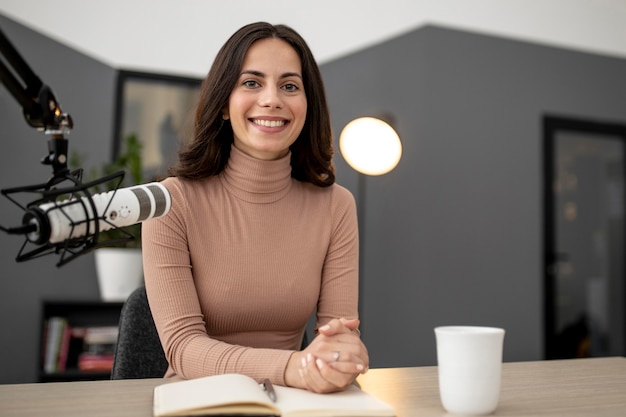 Smiley-Frau mit Mikrofon und Kaffee in einem Radiostudio