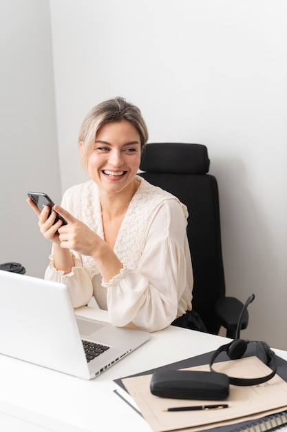 Smiley-Frau mit mittlerem Schuss am Schreibtisch