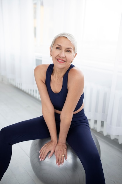 Kostenloses Foto smiley-frau mit mittlerem schuss auf gymnastikball