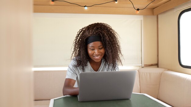 Smiley-Frau mit mittlerem Schuss, die am Laptop arbeitet