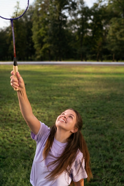 Kostenloses Foto smiley-frau mit mittlerem schuss, die badminton spielt