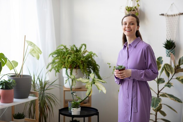 Smiley-Frau mit mittlerem Schuss, die Blumentopf hält