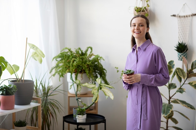 Smiley-Frau mit mittlerem Schuss, die Blumentopf hält