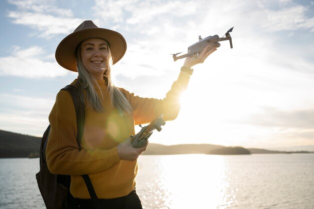 Smiley-Frau mit mittlerem Schuss, die draußen eine Drohne hält