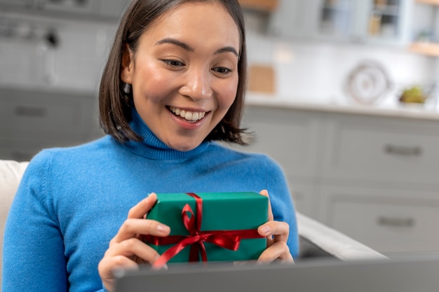 Kostenloses Foto smiley-frau mit mittlerem schuss, die ein geschenk hält