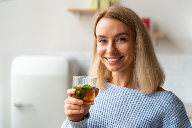 Smiley-Frau mit mittlerem Schuss, die ein Getränk hält