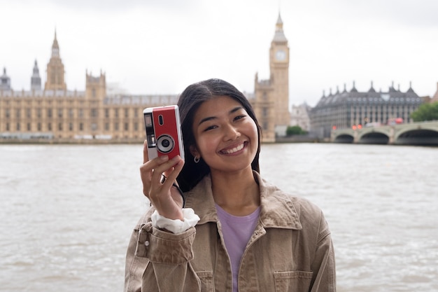 Smiley-Frau mit mittlerem Schuss, die eine Fotokamera hält