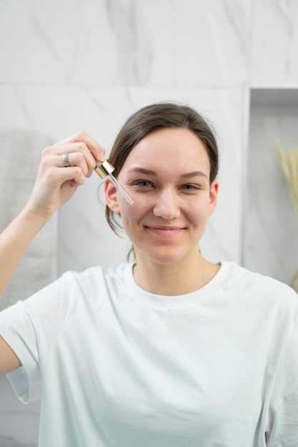 Smiley-Frau mit mittlerem Schuss, die Gesichtsserum verwendet