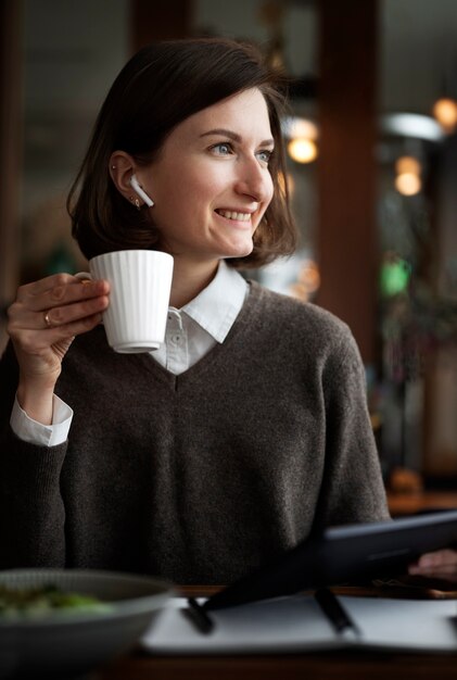 Smiley-Frau mit mittlerem Schuss, die Kaffee hält