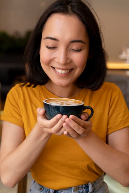 Smiley-Frau mit mittlerem Schuss, die Kaffeetasse hält