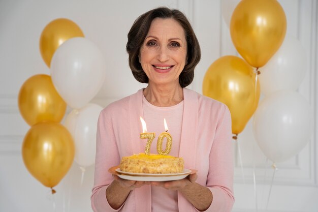 Smiley-Frau mit mittlerem Schuss, die Kuchen hält
