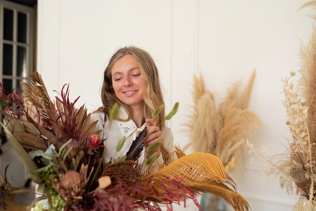 Smiley-Frau mit mittlerem Schuss, die mit getrockneten Blumen arbeitet