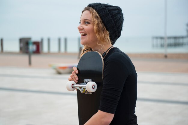 Kostenloses Foto smiley-frau mit mittlerem schuss, die schlittschuh hält