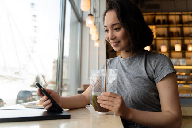 Smiley-Frau mit mittlerem Schuss, die Smartphone hält