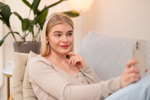 Smiley-Frau mit mittlerem Schuss, die Smartphone hält