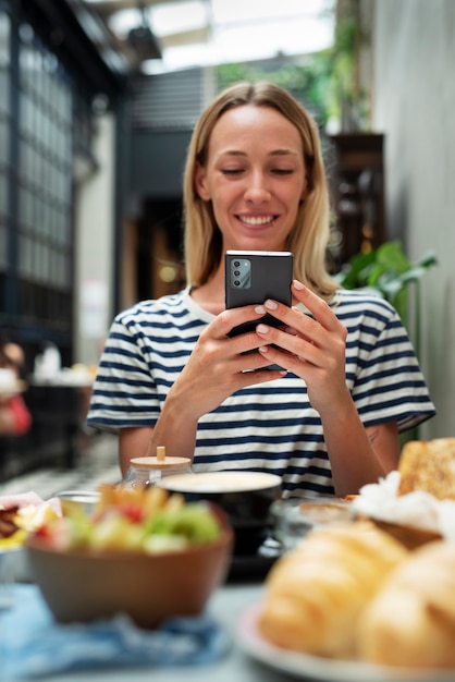 Kostenloses Foto smiley-frau mit mittlerem schuss, die smartphone hält