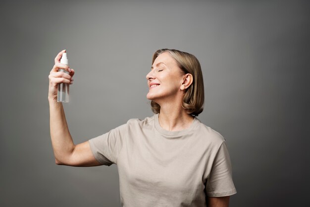 Smiley-Frau mit mittlerem Schuss, die Spray aufträgt