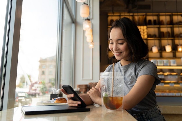 Smiley-Frau mit mittlerem Schuss, die Telefon hält