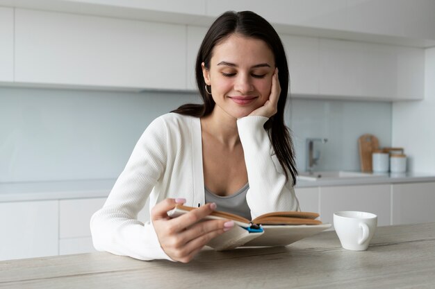 Smiley-Frau mit mittlerem Schuss, die zu Hause liest