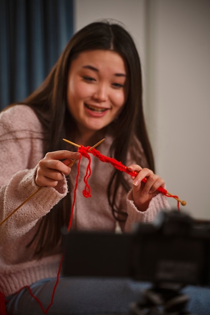 Kostenloses Foto smiley-frau mit mittlerem schuss, die zu hause strickt