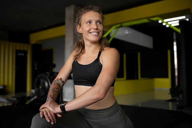 Smiley-Frau mit mittlerem Schuss im Fitnessstudio