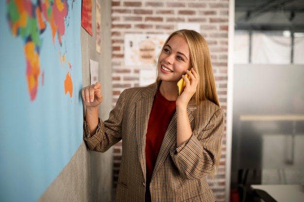 Smiley-Frau mit mittlerer Aufnahme, die am Telefon telefoniert