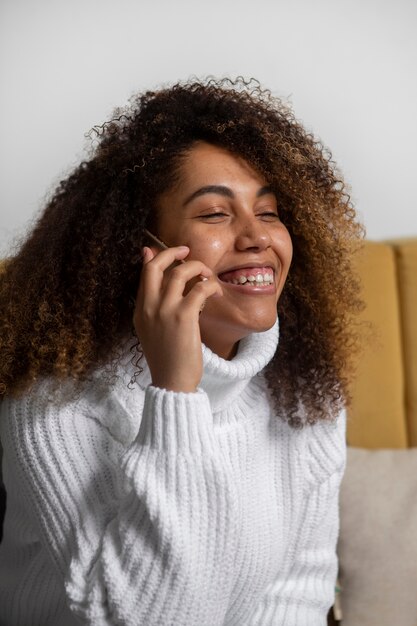 Smiley-Frau mit mittlerer Aufnahme, die am Telefon telefoniert