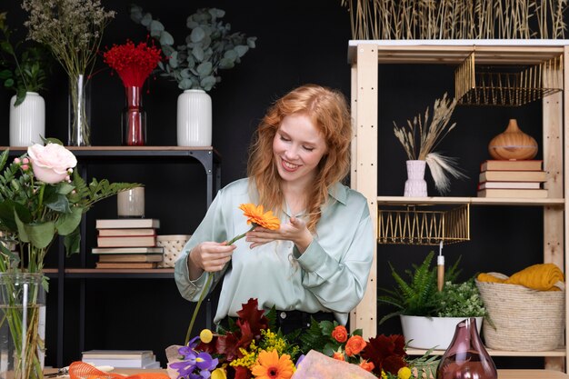 Smiley-Frau mit mittlerer Aufnahme, die eine Blume hält