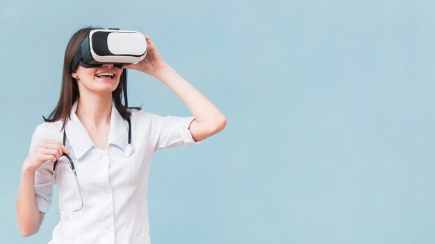 Smiley-Frau mit Stethoskop unter Verwendung des Virtual-Reality-Headsets