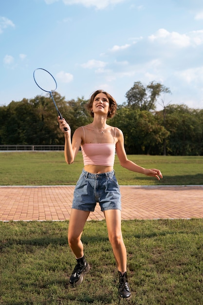 Smiley-Frau mit vollem Schuss, die Badminton spielt