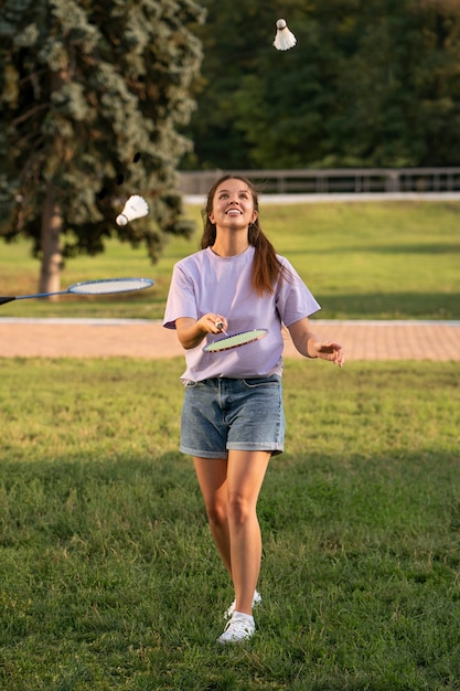 Smiley-Frau mit vollem Schuss, die Badminton spielt